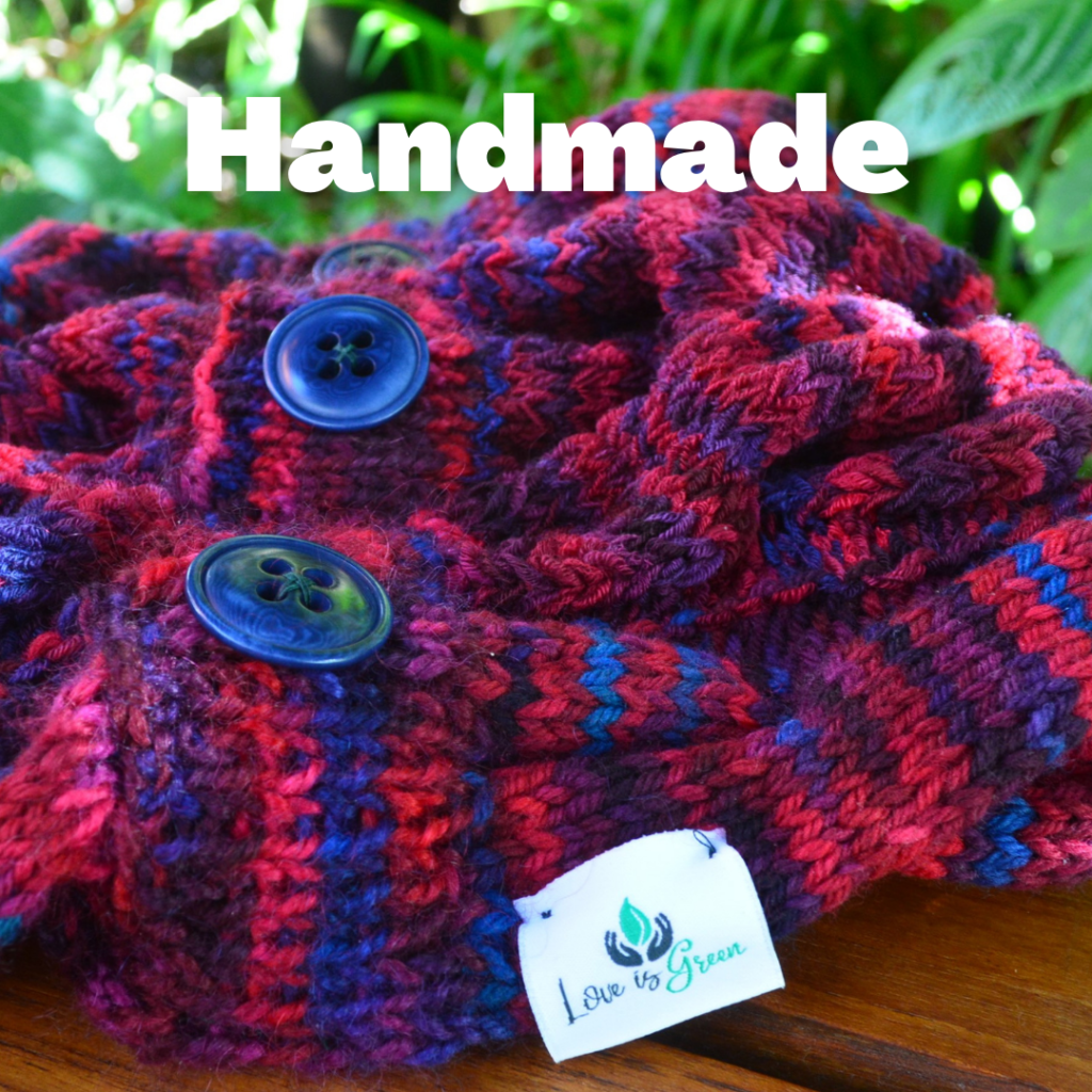 A brightly coloured knitted cowl with blues, pinks and purples, in the foreground a tag that reads Love is Green. Text reads: Handmade
